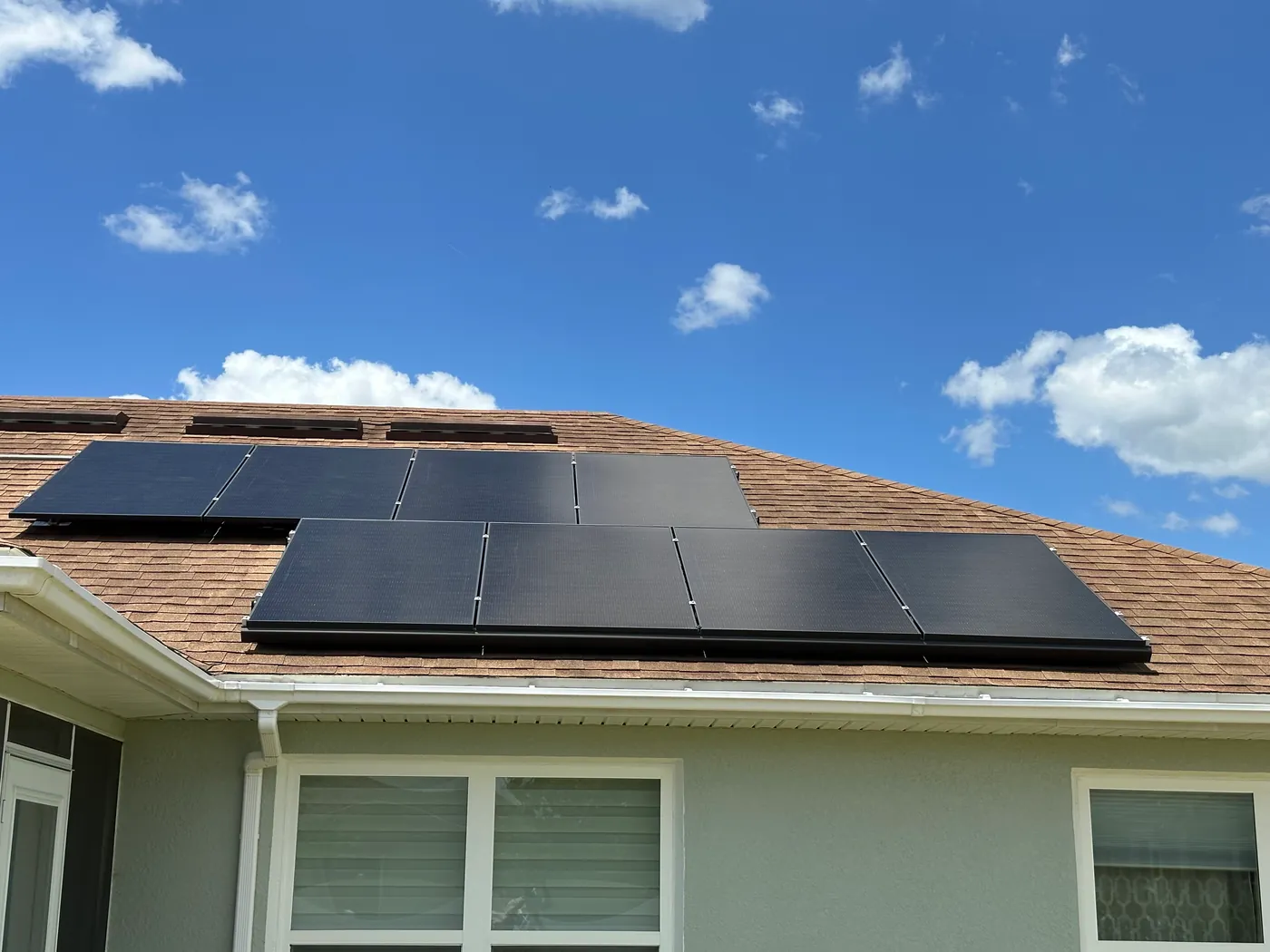 Black solar panels on a Sunstorm customer's roof beneath a blue sky